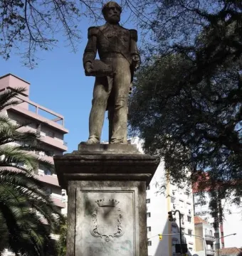 The Conde de Porto Alegre monument, a weathered statue of a bearded man in military uniform on a carved stone pedestal.