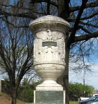 The Cuban Friendship Urn on a tiered pedestal with carved relief details and a bronze plaque.