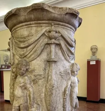 Four Seasons Altar with carved reliefs, a central vessel, and two winged figures on a textured stone base.