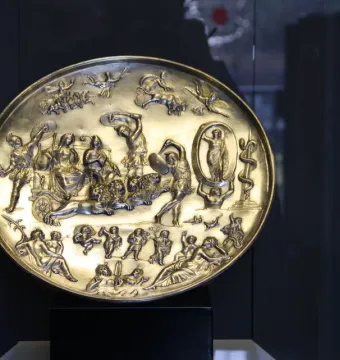 The Parabiago Plate, a gold-toned circular relief with a central chariot scene and surrounding mythological figures.
