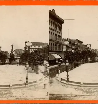 The Tyler Davidson Fountain stands at the far end of a paved public square lined with trees and ornate lampposts.
