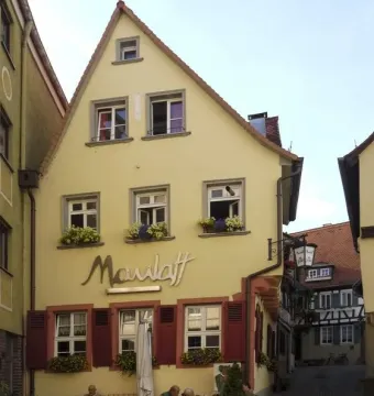 The Aschaffenburger Maulaff restaurant with outdoor seating on a cobblestone square.