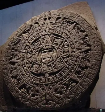 Aztec Sun Stone with intricate carved symbols and a central face surrounded by concentric rings.