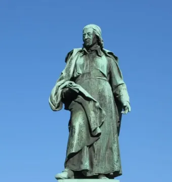 Vodnik Monument, a green-patinated statue of a man in historical clothing holding a rolled document on a white pedestal.