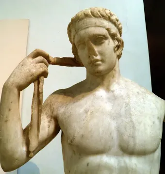 Farnese Diadumenos marble bust with a band on his head, holding a ribbon in his raised right hand.