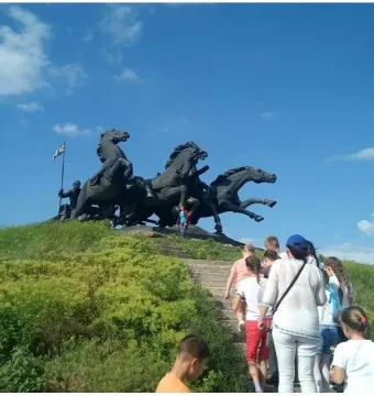 Legendary Tachanka monument with rearing horses and a flag-bearing figure on a green hill.