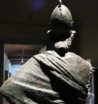Rear view of Minerva d\'Arezzo showing the crested helmet, detailed hair, and draped clothing with a green and brown patina.