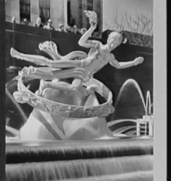 Prometheus statue inside a large ring above a tiered fountain with cascading water and onlookers in the background.