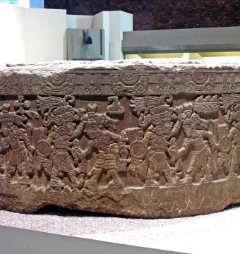 Stone of Motecuhzoma I with a carved cylindrical frieze of figures in elaborate headdresses.