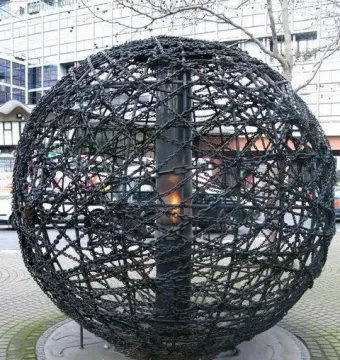 Universal Links on Human Rights sculpture with a dark spherical frame of chains and bars surrounding a central flame.