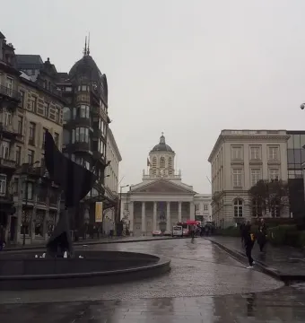 The Whirling Ear sculpture rises from a circular basin beside an urban street scene.