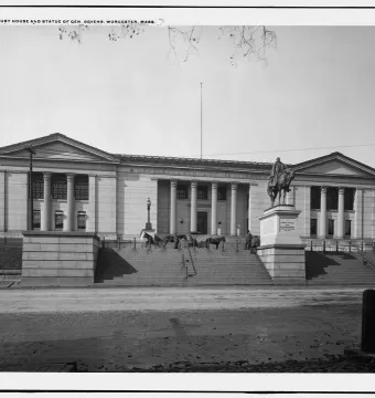 Charles Devens statue on horseback atop a tall pedestal in front of a columned courthouse.