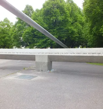 Klagebalken, a long stone monument with text, balanced on a central block in a paved park setting.