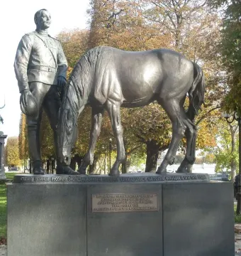Monument to the Russian Expeditionary Force showing a uniformed man beside a horse with its head lowered, on a stone pedestal with Cyrillic and French inscriptions.