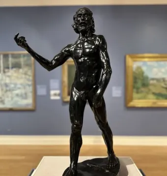Saint John the Baptist by Auguste Rodin, a dark bronze sculpture of a gaunt male figure with an intense upward gaze and one arm extended.