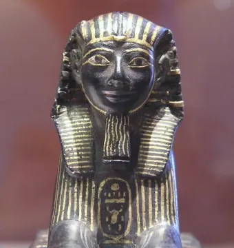 Thutmose III sphinx with a striped headdress, false beard, and gold inlays on its body and chest cartouche.