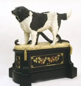 Bashaw sculpture of a black and white dog standing over a snake on a decorative pedestal.