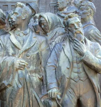 Bronze relief on the Branting Monument showing a bearded man in a suit, a mustached man, and a woman in a crowd.