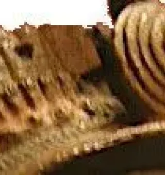Close-up of the Bronze Head from Ife showing textured brownish-gold metal with raised ridges and spiral ribbed patterns.