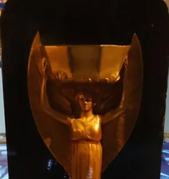 Jules Rimet Trophy with a winged female figure holding a cup above her head on a dark pedestal.