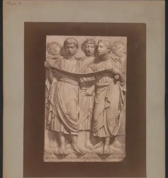 Cantoria relief sculpture with a choir of robed figures holding a scroll and singing.