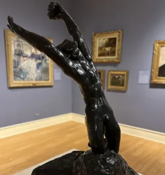 Rodin\'s The Prodigal Son sculpture showing a nude male figure kneeling with arms thrown upward in a museum gallery.