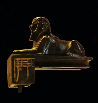 Thutmose III sphinx figurine in profile with gold inlays on a dark background