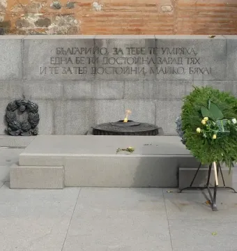 Unknown Soldier Monument with a granite memorial wall, Cyrillic inscriptions, and an eternal flame in a circular basin.