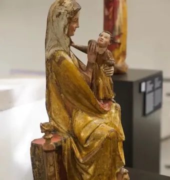 Virgin on a Wide Throne, a weathered wooden sculpture of a seated robed woman holding a child.