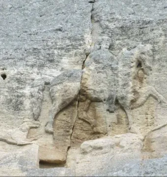Madara Rider rock relief carved into a grey cliff face, with a vertical crack running through the carving.