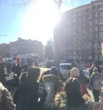 Mahatma Gandhi memorial statue with a crowd gathered nearby on a city street in Washington, DC
