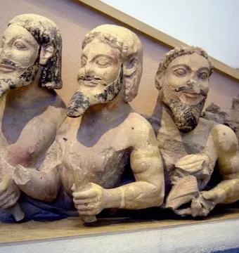 Trisomatos Typhon sculpture showing three male figures joined side by side, with dark traces of beard and hair and faint red pigment.