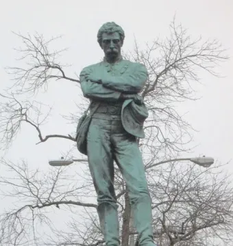 Appomattox bronze statue of a mustached man in military dress standing with arms crossed on a tiered stone pedestal.