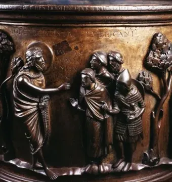 Detail of the Baptismal Font at St Bartholomew\'s Church showing a haloed figure addressing robed men in relief sculpture.