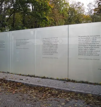 Translucent memorial panels with white multilingual text at the Memorial to the Murdered Sinti and Roma of Europe.