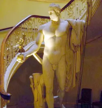 Napoleon as Mars the Peacemaker, a nude marble statue of a muscular male figure holding an orb and staff beside an ornate staircase.