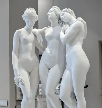 The Three Graces, a white marble sculpture of three female figures in a museum gallery.