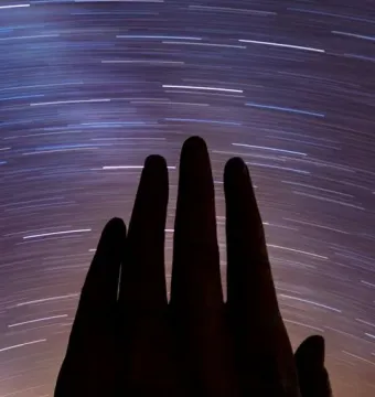 Mano del Desierto sculpture under arcing star trails in the night sky.