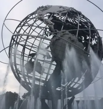 The Unisphere steel globe sculpture with orbital rings, surrounded by water fountains under an overcast sky.