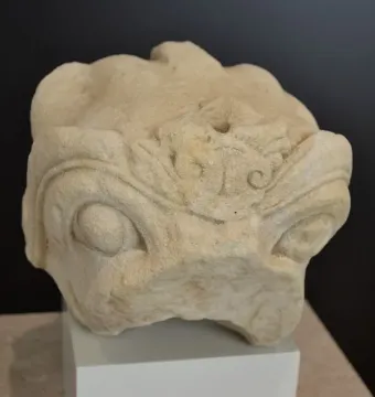 Stone head of the Grifo de Redován with rounded eyes and ornate carved details on the forehead and top surface.