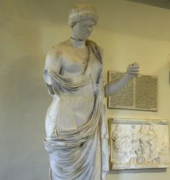 Damaged white marble statue of Armed Aphrodite with a bowed head and one arm missing.