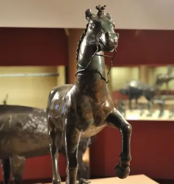 Bronze horse statue from the Neuvy-en-Sullias Hoard, shown with one front leg raised on a rectangular base.