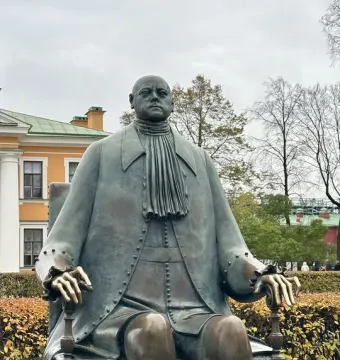 Peter I Monument showing a bronze seated figure in a long coat and cravat among low bushes.
