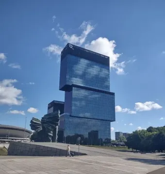 Silesian Insurgents\' Monument with three jagged dark forms on a stone base beside a glass skyscraper and domed building.