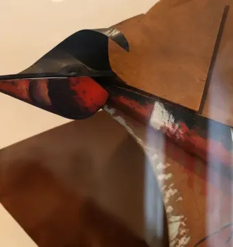 Close-up of Dynamism of a Speeding Horse + Houses showing a pointed protrusion with red and black curved shapes on a brown surface.