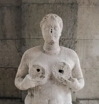 Fontana delle Tette stone sculpture of a female torso with cupped breasts and a simplified face with small perforations.