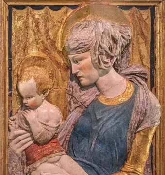 Painted terracotta Madonna and Child relief with halos and worn, cracked surfaces.