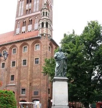 Nicolaus Copernicus Monument showing a bronze robed figure holding an astrolabe and pointing upward in a city square.