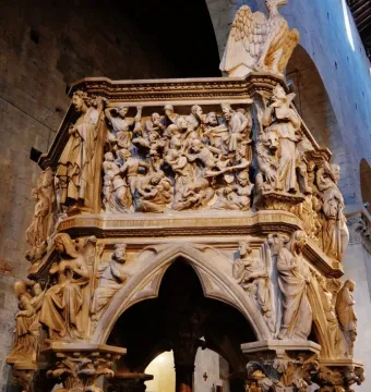 Sant\' Andrea Pulpit with densely carved figures, a large eagle, and Gothic arches inside a church interior.