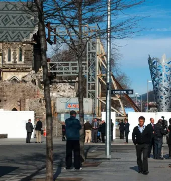 The Chalice rises in the background behind a low white barrier in Cathedral Square, with several people standing nearby.